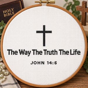 May include: A circular wooden embroidery hoop containing white Aida fabric with black cross-stitched text that reads The Way The Truth The Life and JOHN 14:6, centered below a black cross-stitched Christian cross symbol on the fabric.