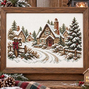 May include: A framed cross-stitch embroidery depicting a winter scene with a wooden cabin, snow-covered pine trees, and a fence. The cabin features a red door and a brick chimney. The scene is rendered in shades of brown, green, and white.