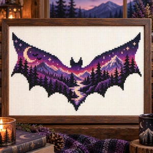 Può includere: Un ricamo a punto croce incorniciato che presenta una sagoma a forma di pipistrello riempita con un paesaggio. Il disegno raffigura un tramonto viola e rosa su montagne, un fiume tortuoso e pini scuri sotto una luna crescente e stelle.