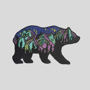 May include: An embroidered patch in the shape of a bear. The interior of the bear silhouette features a landscape scene with purple and green mountains, dark green pine trees, and a dark blue night sky with yellow stars and a crescent moon.