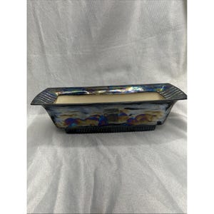 May include: A rectangular ceramic planter featuring an iridescent, multi-colored glaze with metallic blue, purple, and gold tones. The vessel has a flared rim with a ribbed texture and a matching ribbed base, while the interior is a matte cream color.