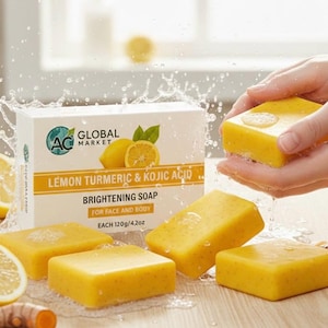 May include: A rectangular box of Lemon Turmeric & Kojic Acid Brightening Soap labeled 120g/4.2oz, accompanied by four yellow soap bars, fresh lemon slices, and turmeric roots, with water splashing around the products.