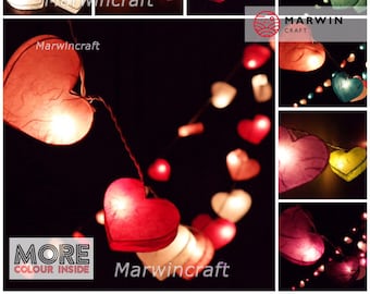 May include: A string of heart-shaped paper lanterns with warm white lights. The lanterns are in various colours, including red, pink, white, yellow, blue, and green. The string is labelled "Marwincraft".