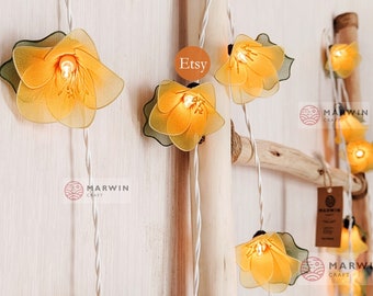 May include: String lights with yellow flower-shaped fabric shades. The lights are strung on a white cord and are hanging from a wooden ladder. The text "Etsy" and "Marwin Craft" is visible in the image.