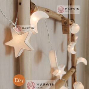 Könnte beinhalten: Eine Lichterkette mit weißen Lichtern in Stern- und Halbmondform. Die Lichter sind an einer Holzleiter befestigt, auf der der Text "MARWIN CRAFT" und "Etsy" zu sehen ist.