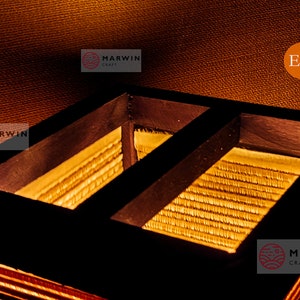 May include: Close-up of a wooden lampshade with a woven bamboo interior. The lampshade is lit from within, casting a warm glow. The text "Marwin Craft" is visible on the bottom right corner of the image.