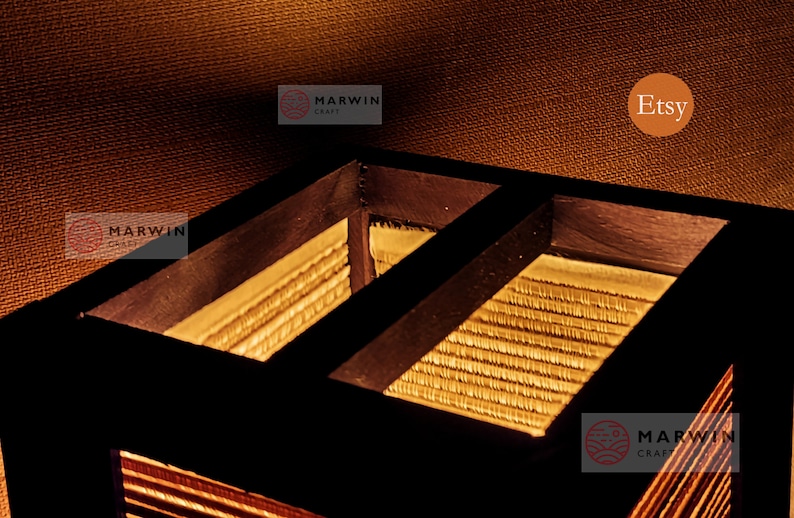 May include: Close-up of a wooden lampshade with a woven bamboo interior. The lampshade is lit from within, casting a warm glow. The text "Marwin Craft" is visible on the bottom right corner of the image.