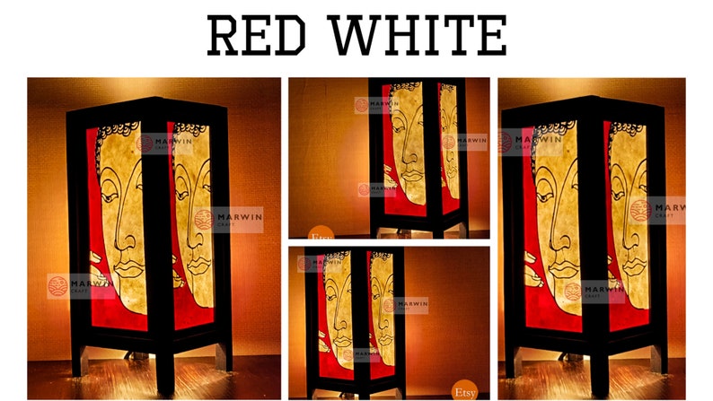 May include: A wooden table lamp with a red and white design featuring a Buddha face. The lamp is lit and has a warm glow.