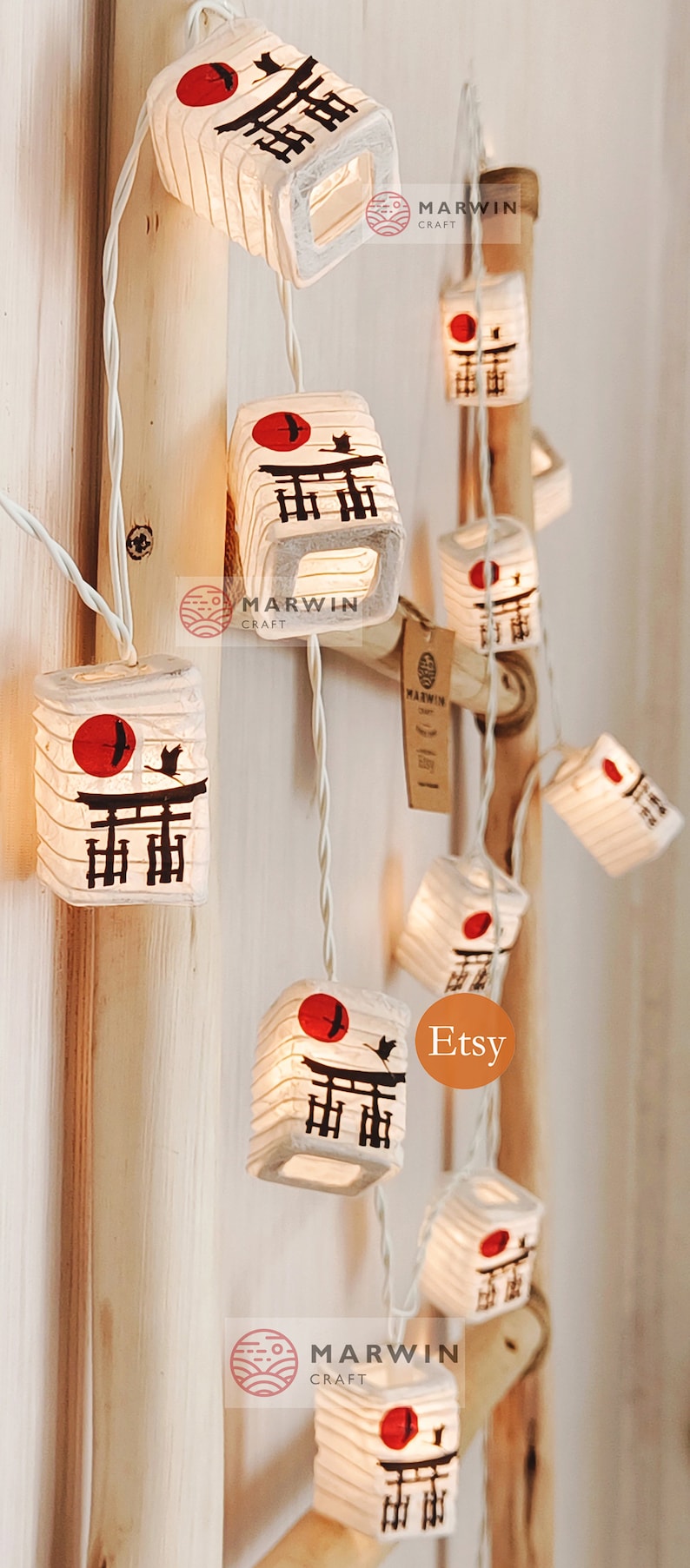 K&ouml;nnte beinhalten: Eine Lichterkette aus wei&szlig;en Papierlaternen mit einer roten Sonne und einer schwarzen Silhouette eines japanischen Tempeltors. Die Laternen sind beleuchtet und h&auml;ngen an einem wei&szlig;en Draht. Der Text "Marwin Craft" und "Etsy" ist auf dem Bild zu sehen.