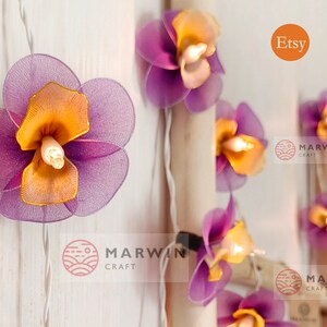 Puede incluir: Luces de cadena de flores de tela de color morado y naranja con un cable blanco. Las luces est&aacute;n enhebradas con un cable blanco y tienen una peque&ntilde;a bombilla en el centro de cada flor. Las flores est&aacute;n hechas de una tela suave y delicada y tienen un aspecto ligeramente fruncido. Las luces son perfectas para agregar un toque de fantas&iacute;a y encanto a cualquier espacio.