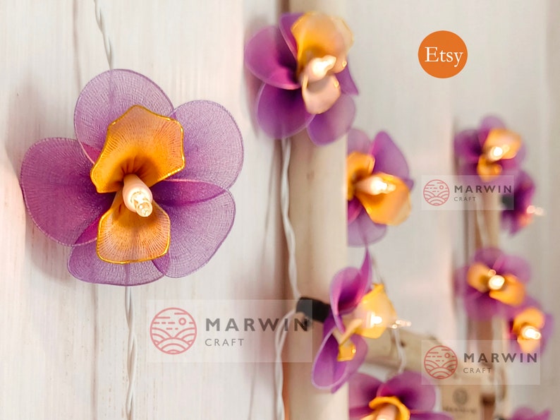 Puede incluir: Luces de cadena de flores de tela de color morado y naranja con un cable blanco. Las luces est&aacute;n enhebradas con un cable blanco y tienen una peque&ntilde;a bombilla en el centro de cada flor. Las flores est&aacute;n hechas de una tela suave y delicada y tienen un aspecto ligeramente fruncido. Las luces son perfectas para agregar un toque de fantas&iacute;a y encanto a cualquier espacio.