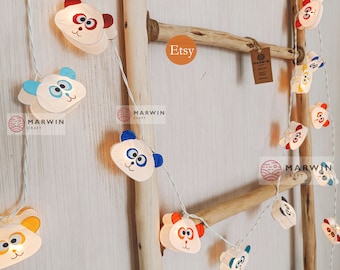May include: String of lights with panda bear faces, each with a different colored accent. The lights are strung on a wooden ladder with the word "Etsy" written on it. The lights are made by "Marwin Craft".