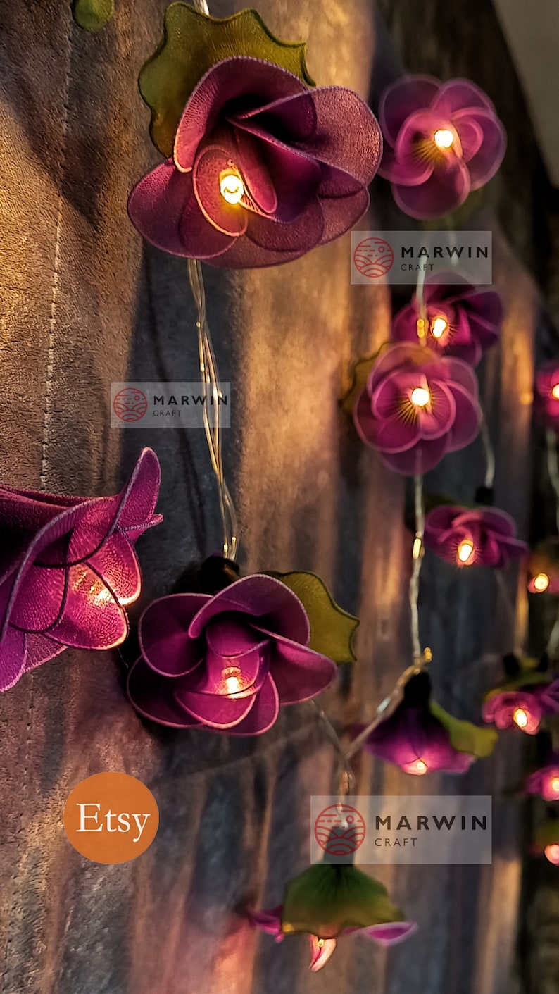 May include: Purple fabric flower string lights with warm white LED lights. The lights are strung on a copper wire and are perfect for adding a touch of whimsy to any space. The flowers are made of a soft, delicate fabric and have a slightly ruffled texture. The lights are battery operated and come with a remote control.