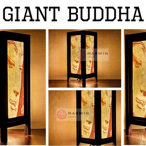 May include: A wooden table lamp with a light brown shade featuring a stylized image of a Buddha. The lamp has a black base and a black cord. The lamp is lit and casting a warm glow. The lamp is labeled "Marwin Craft" and "Etsy".
