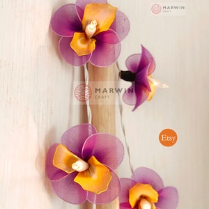 Puede incluir: Una cadena de luces con bombillas en forma de flores de color morado y amarillo. Las luces est&aacute;n enhebradas en un cable blanco y est&aacute;n encendidas. Las flores est&aacute;n hechas de tela y tienen un aspecto delicado y femenino. Las luces son perfectas para a&ntilde;adir un toque de fantas&iacute;a y encanto a cualquier espacio.