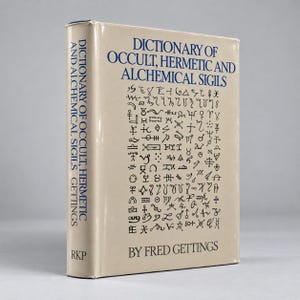 May include: A hardcover book titled Dictionary of Occult, Hermetic and Alchemical Sigils by Fred Gettings. The beige dust jacket features dark blue text and a grid of various black alchemical symbols on the front cover and spine.