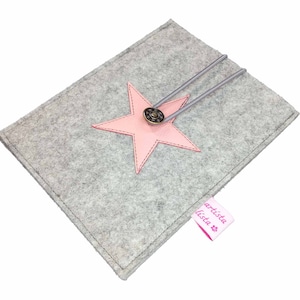 May include: Grey felt laptop sleeve with a pink leather star and a button closure. The sleeve has a pink label that says "artista lista".