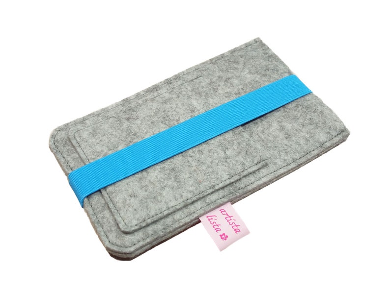 May include: Grey felt phone case with a blue elastic band and a pink label that says "artista lista".