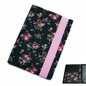 Könnte beinhalten: Schwarze E-Reader-Hülle mit Blumenmuster und rosa Gummizug. Die Hülle ist geöffnet und zeigt einen schwarzen E-Reader mit einem Bildschirm, auf dem ein digitales Buch angezeigt wird.