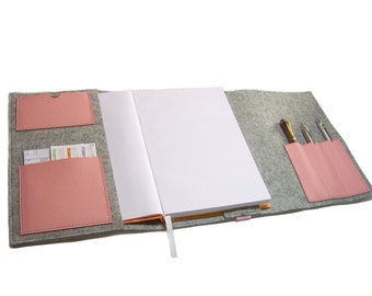 May include: A gray felt notebook cover with pink leather pockets and pen slots. The cover has a white notebook inside.