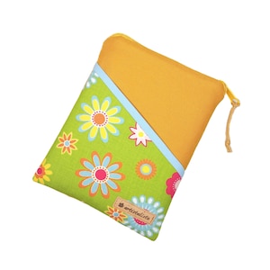 Könnte beinhalten: Eine floral bedruckte Tasche mit diagonalem Farbblock-Design. Die Tasche hat einen grünen Hintergrund mit bunten Blumen, einen hellblauen Streifen und eine senfgelbe Oberseite. Der Reißverschluss ist gelb und die Tasche hat ein kleines Etikett mit der Aufschrift "artistalisa".