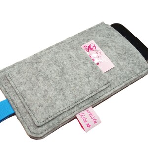 May include: Grey felt phone case with a blue strap and a pink pocket with the text "artista lista" on it.