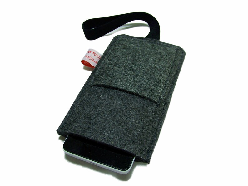May include: A gray felt phone case with a black strap and a small pocket on the front. The case has a red label with the text "#C-Store" on it.