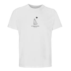 Pode incluir: Uma t-shirt branca de manga curta com um pequeno desenho de linha preta de um gato sentado sob uma forma rabiscada. Abaixo do gato, o texto diz: no reason to worry. found one. O design está centrado no peito da peça de vestuário.