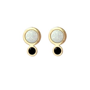 May include: A pair of gold earrings with white opal and black stones. The earrings are round and have a simple design.