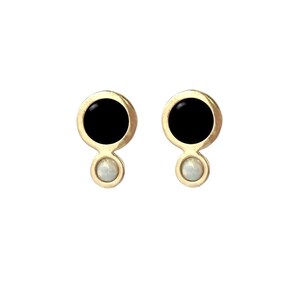 May include: A pair of gold earrings with black and white round stones. The earrings have a simple, modern design.