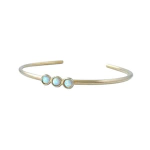 May include: A gold bangle bracelet with three small opal stones.