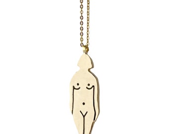 Op de afbeelding: Een gouden ketting met een hanger in de vorm van een vrouwelijke figuur. De hanger is gemaakt van metaal en heeft een eenvoudige lijntekening van een vrouwenlichaam.