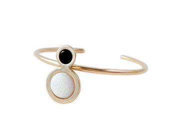 May include: Gold ring with a white opal and black stone in a circle design.