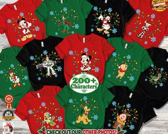 Puede incluir: Una colección de camisetas rojas, verdes y negras con varios personajes de Disney, incluyendo a Mickey Mouse, Minnie Mouse, el Pato Donald, Goofy, Pluto, Winnie the Pooh y Buzz Lightyear, decoradas con luces navideñas y copos de nieve.