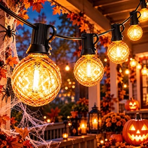 May include: A string of outdoor globe lights featuring textured, amber-colored glass bulbs with black sockets. The lights are suspended in a row, emitting a warm glow, and are decorated with artificial autumn leaves and white spider webs.