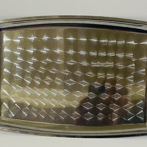 Puede incluir: Una bandeja de servicio rectangular de metal plateado con un acabado pulido y un patrón de diamantes repetido en la base. La bandeja incluye dos asas de metal dorado ornamentadas fijadas en los lados izquierdo y derecho.