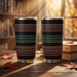 May include: Two black stainless steel tumblers with silver rims and bases, featuring a repeating horizontal pattern of pink, teal, and light blue geometric lines, zigzags, and arches printed around the exterior of each cylindrical vessel.