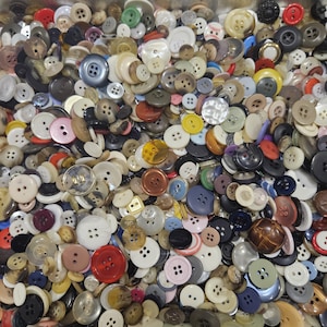 May include: A large collection of assorted sewing buttons in various sizes, shapes, and colours, including white, black, red, blue, brown, and green, featuring two-hole and four-hole designs made from plastic, wood, and metal materials.