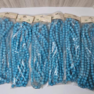 May include: Six individual clear plastic bags containing strands of round, bright blue wooden beads. Each bag is topped with a beige cardboard header card featuring the text "中国" and "SHANGHAI" printed in black ink at the top.