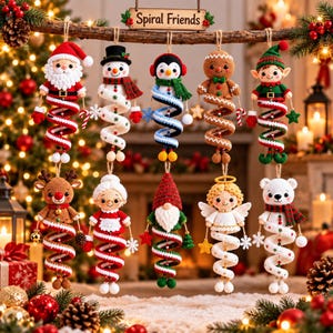 Op de afbeelding: Tien gehaakte kerstornamenten hangen aan een houten tak met het label Spiral Friends. De figuren zijn de kerstman, een sneeuwpop, een pinguïn, een peperkoekmannetje, een elf, een rendier, mevrouw de kerstman, een kabouter, een engel en een ijsbeer.