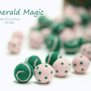 May include: A close-up of green and pink felt balls with polka dots and swirl designs. The balls are arranged on a white surface. The text "Emerald Magic" and "Polka Dot and Swirl Felt Balls" is visible in the background.