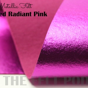 May include: Metallic felt in a brushed radiant pink color. The felt is folded over, showing the texture of the fabric.