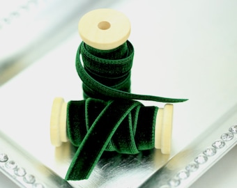 May include: Two spools of emerald green velvet ribbon with wooden spools. The ribbon is on a silver tray with a crystal border.