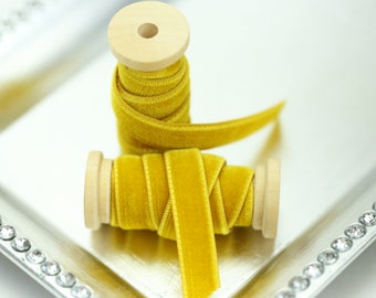 May include: Two spools of yellow velvet ribbon, each wound around a wooden spool. The ribbon is a bright, sunny yellow color.