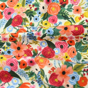 May include: Fabric featuring a vibrant floral design on a cream background. The pattern includes red, pink, orange, and blue flowers, alongside green foliage. The flowers are densely packed across the fabric's surface.