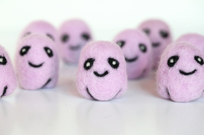 May include: A group of eight small, purple, felt balls with black embroidered eyes and smiling mouths.