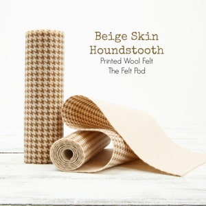May include: Beige and white houndstooth patterned wool felt fabric rolled up. The fabric is labelled "Beige Skin Houndstooth" and "Printed Wool Felt The Felt Pod".