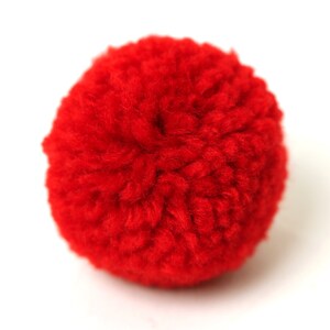 May include: A bright red fluffy pom pom made of yarn.