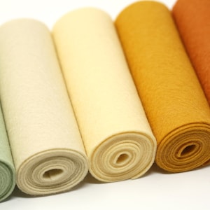 Puede incluir: Seis rollos de fieltro en varios tonos de verde, crema, amarillo, naranja y rojo. Los rollos est&aacute;n dispuestos en una fila de izquierda a derecha, con el rollo verde a la izquierda y el rollo rojo a la derecha.