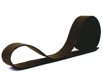 May include: A roll of brown felt ribbon. The ribbon is about 1 inch wide and is rolled up in a loose coil.